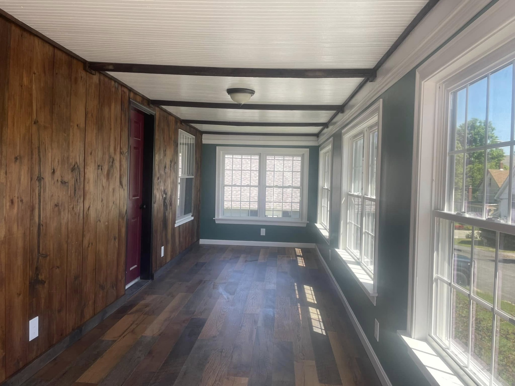 Finished porch renovation with restored wood wall and new windows