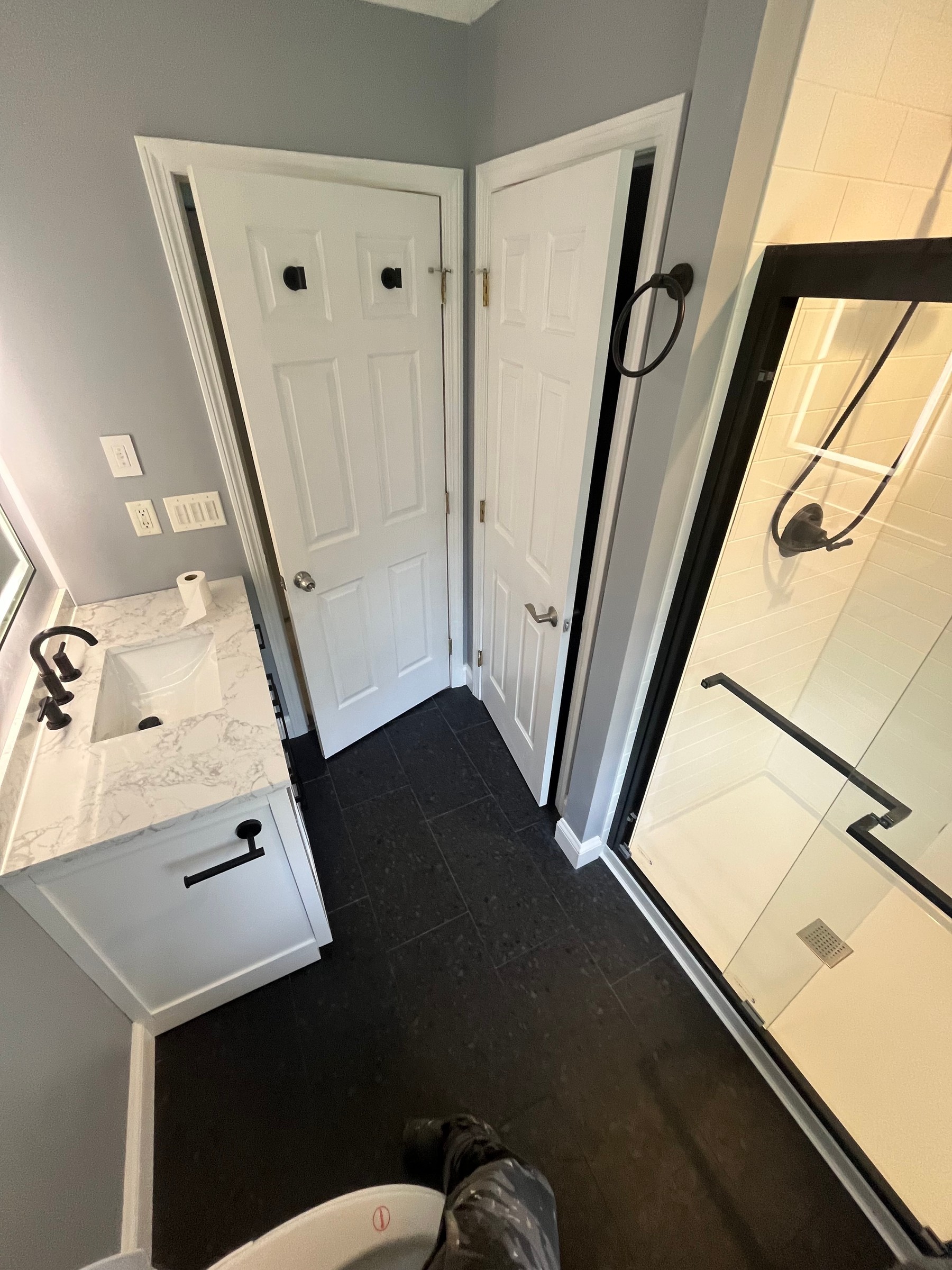 Finished bathroom with dark tile, white vanity, and glass shower