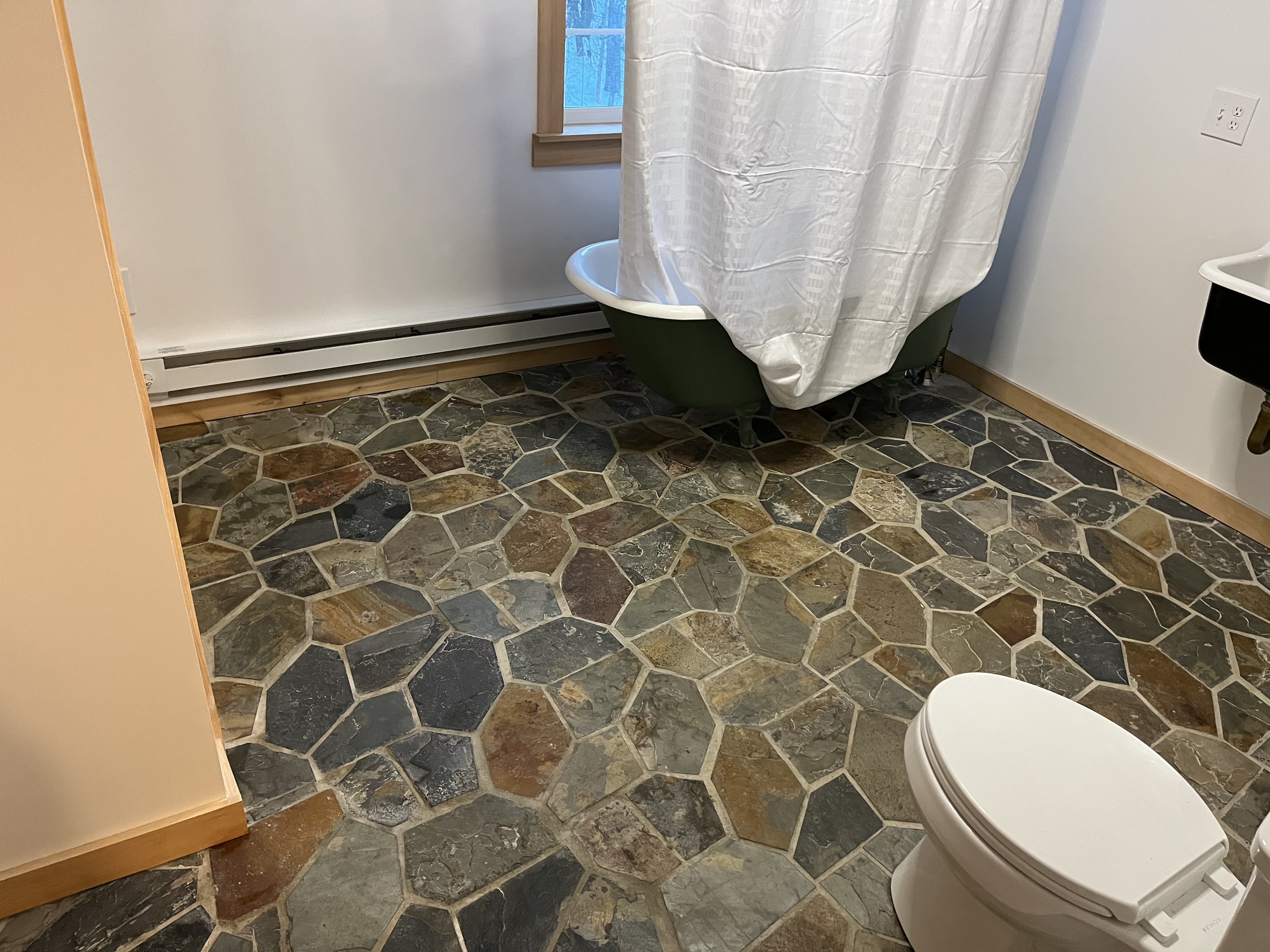 Bathroom finished with a natural stone mosaic floor and clawfoot tub